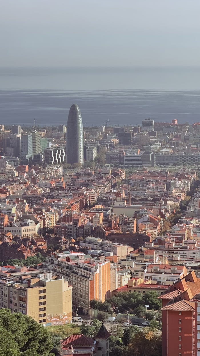 Aerial view of Barcelona showcasing the Torre Glòries and cityscape against the backdrop of the sea.