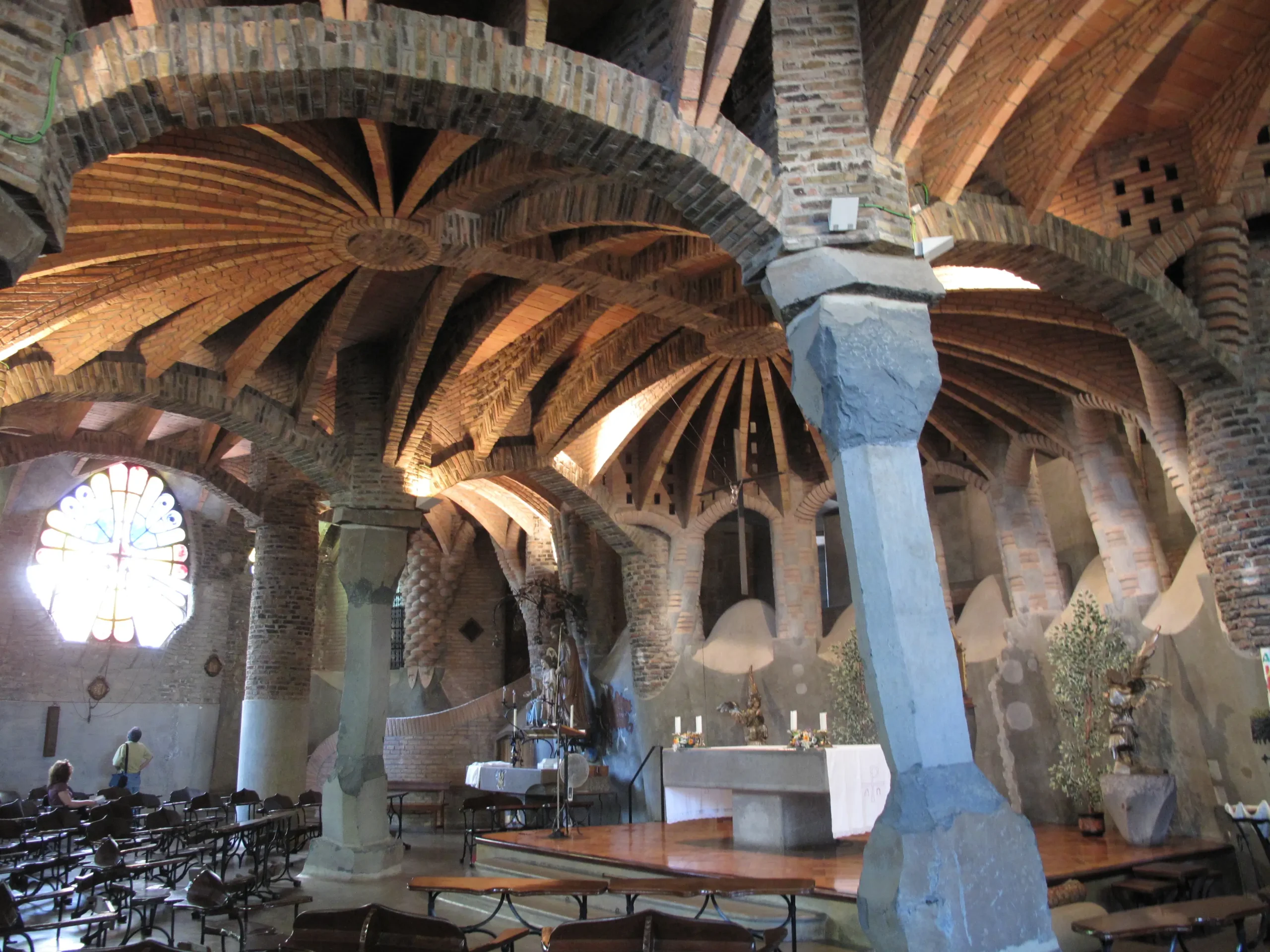 Interior de la Cripta Gaudí en Colonia Güell, mostrando sus innovadoras columnas inclinadas y bóvedas parabólicas de ladrillo.